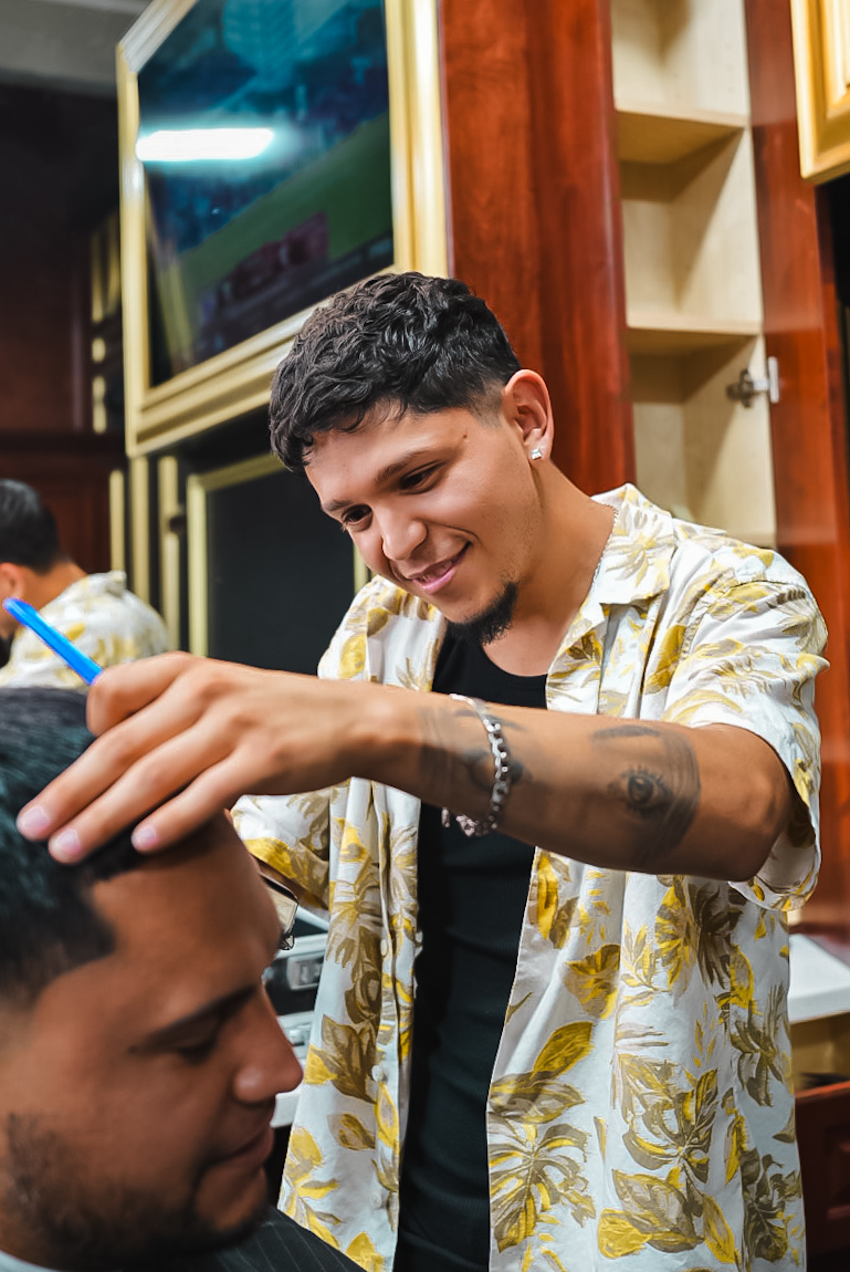 Famous Fadez barber smiling while cutting a client’s hair
